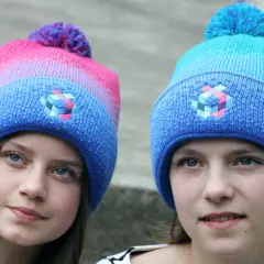 Zwei Mädchen mit bunten Bommelmützen in Blau und Pink.